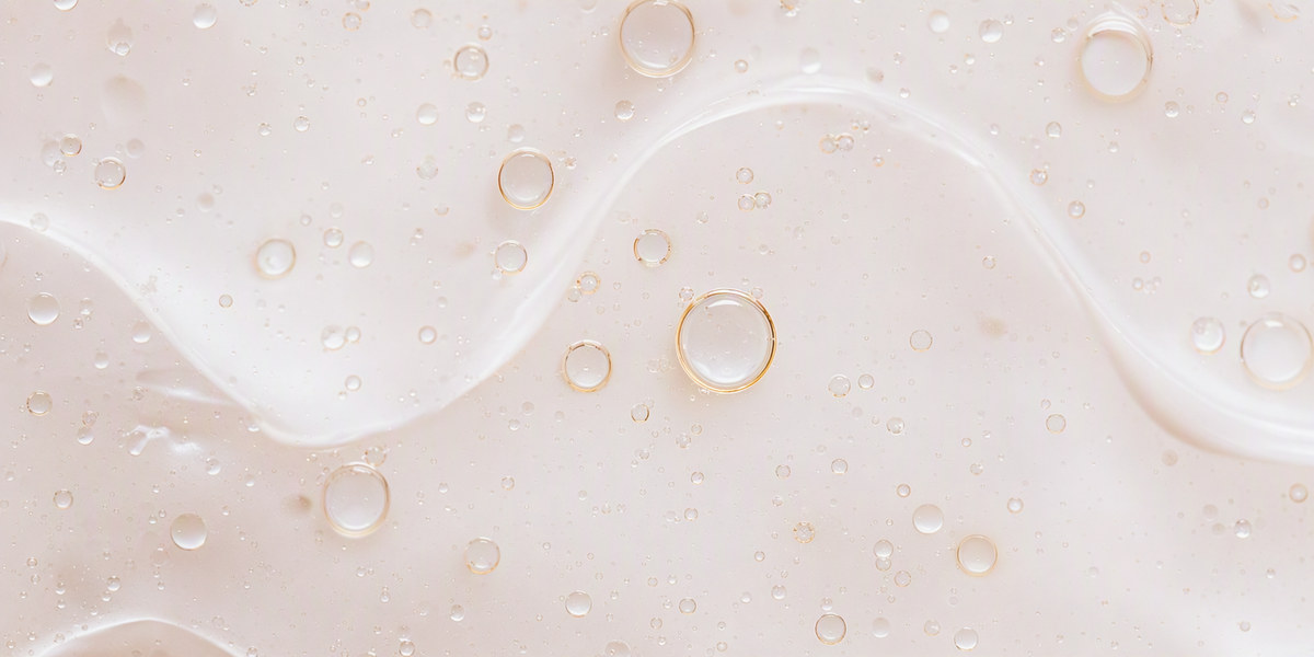 Macro close-up of a light cosmetic emulsion with fine suspended oil droplets